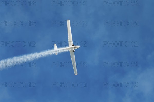 Stunt aerobatic plane performing stunts in blue sky with smoke trail. Concept of speed, difficulty,
