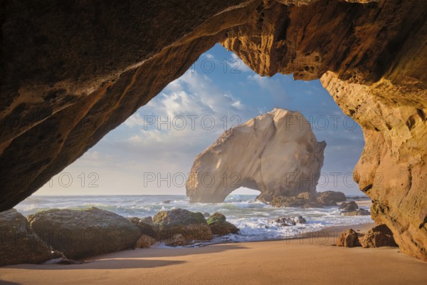 Penedo do Guincho, a large boulder rock arch at Praia da Santa Cruz, Portugal, with ocean waves and