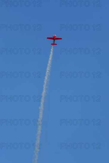 Red stunt aerobatic plane performing stunts in blue sky. Concept of speed, difficulty, precision,