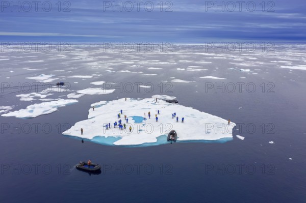 Aerial view over ecotourists from Iceland Pro Cruises walking on ice floe drifting in the Arctic