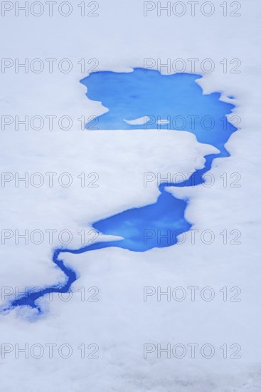Aerial view over vivid blue water of meltpond / melt pond / meltwater pool on sea ice in the Arctic