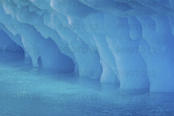 Dripping blue ice pattern from erosion by sea water on base of melting iceberg in the Arctic Ocean