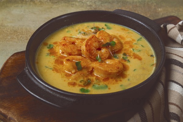 Creamy shrimp curry with spices, garnished with herbs, on a textured background, homemade, no
