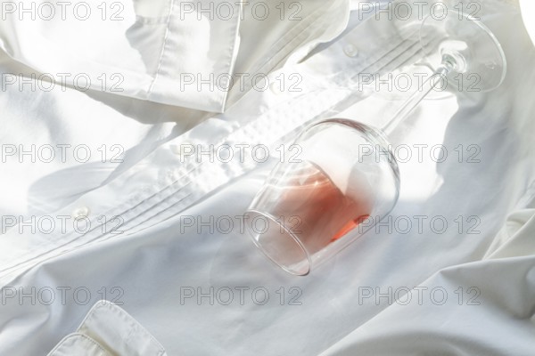 Glass, with pink wine, spilled on a white shirt, close-up, selective focus, no people, concept, top
