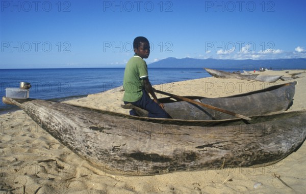 Local boy sitting on a dugout near Kande Beach on Lake Malawi, Malawi, Africa, July 2000, vintage,