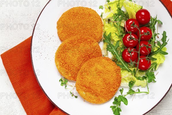 Crispy fried fish cutlets, fish burgers, on a white plate, with fresh lettuce leaves, arugula and