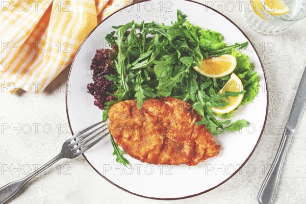 Milanese chicken, Crispy breaded chicken served, with fresh herbs, and lemon wedges