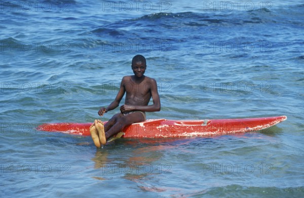 Teenager sitting on a surfboard in Lake Malawi, Kande, Malawi, Africa, July 2000, vintage, retro,