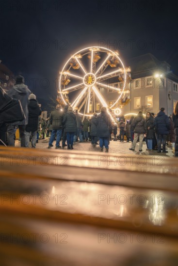 People come together to enjoy an illuminated Ferris wheel at night, Christmas market 2025, Nagold,