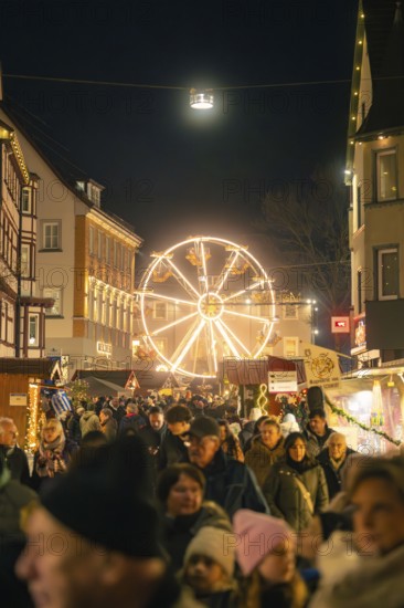 Busy Christmas market at night with illuminated Ferris wheel in the background, Christmas market