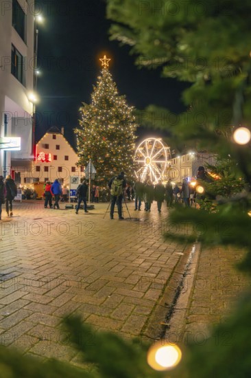 Glowing Christmas tree and Ferris wheel frame a square at night, Christmas market 2025, Nagold,