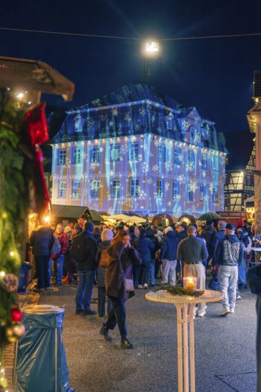 Illuminated building with Christmas projections in front of numerous market visitors, Christmas