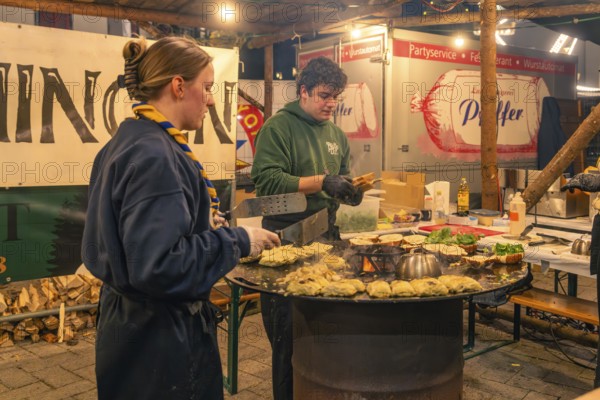 Active chefs prepare food at a stand at a Christmas market, Christmas market 2025, Nagold, Black