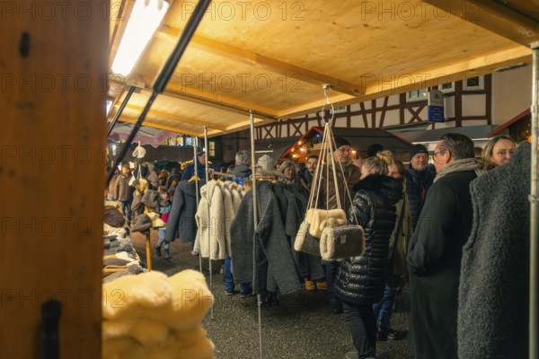 People browse through a range of textiles at a nightly Christmas market, Christmas market 2025,