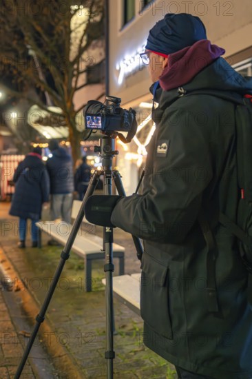 A photographer sets up his camera on the street at night, Christmas market 2025, Nagold, Black