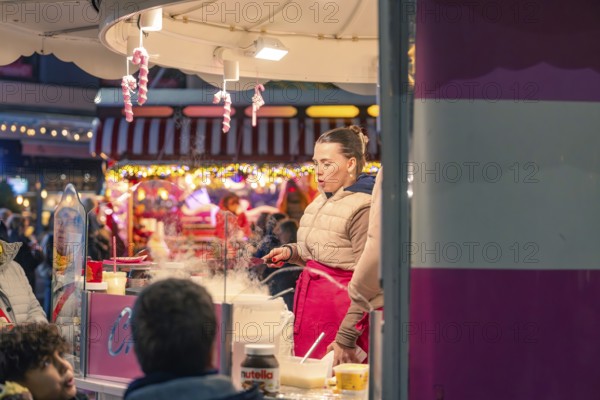 A woman cooks at a market stall surrounded by steaming food and colorful light, Christmas market