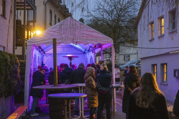 People gather under an illuminated canopy at night, Aidlingen Christmas market, Böblingen district,