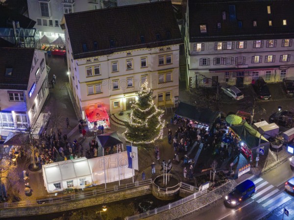Square with illuminated Christmas tree and people gathered at night, Aidlingen Christmas market,