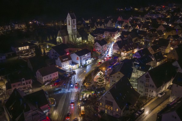 Nighttime city view with decorated Christmas market, church and illuminated streets in a small