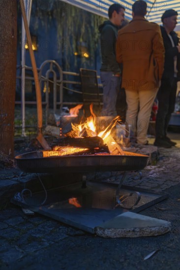 A few people stand next to a warming fireplace at night, Aidlingen Christmas market, Böblingen
