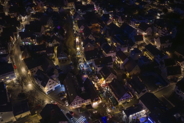 Festively illuminated village at night with lots of people and lights, Aidlingen Christmas market,