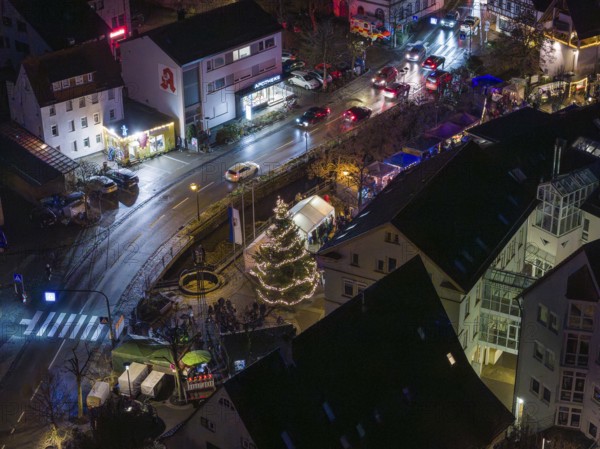 Night scene of a Christmas market with decorated houses and a large Christmas tree in the center,