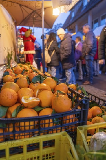 Fresh oranges in boxes in front of curious market visitors in the evening, Aidlingen Christmas