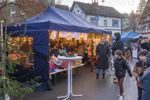 Visitors walk past a tent with Christmas lights and decorations at a Christmas market, Aidlingen