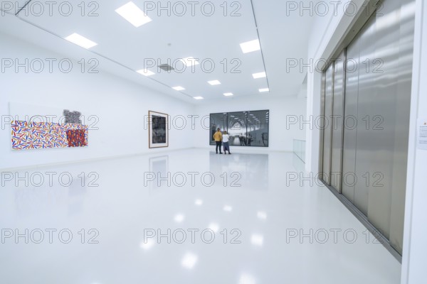 Two people look at works of art in a modern, bright exhibition room, Open Horizons exhibition,