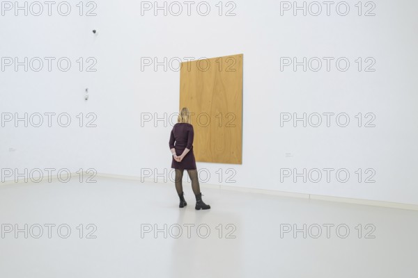 Woman looking at a large, simple, wooden work of art in a minimalistic space, Open Horizons