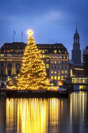 The decorated and illuminated Alster fir tree on the Inner Alster with reflections on the water in