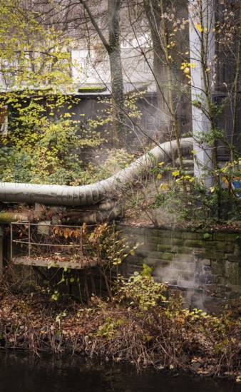 District heating pipeline in front of old industrial buildings on the banks of the Wupper,