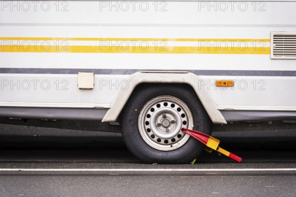 Caravan wheel with yellow-red parking claw parked on a street, Wuppertal, Germany