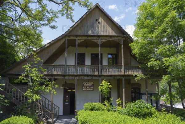 Traditional wooden house with veranda surrounded by green trees and natural ambiance, Old Town,