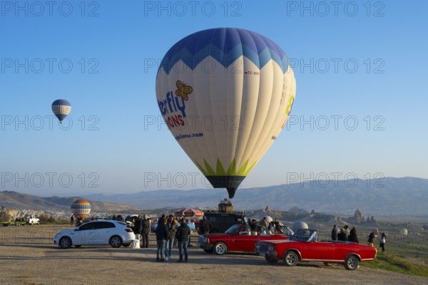 People and cars gather around a large balloon ready to launch, hot air balloons, Göreme National