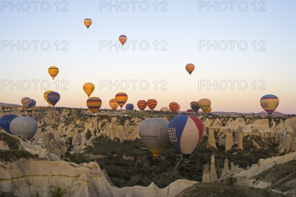 Hot air balloons float over a rocky landscape at dawn, bright colors create a peaceful atmosphere,