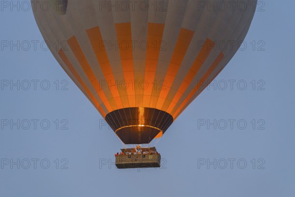 Close-up of glowing hot air balloon with basket and flame against the morning sky, Göreme Tarihî