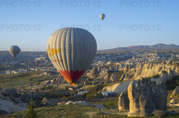 Hot air balloons float over a rocky landscape at sunrise in Capadocia, Göreme National Park, Göreme