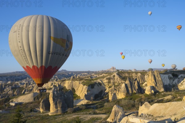 A large colorful hot air balloon moves elegantly over a rocky landscape, Göreme National Park,