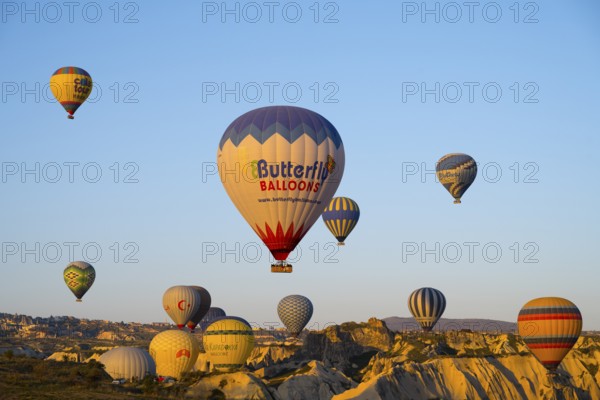 Many colorful hot air balloons rise over rocks early in the morning, Göreme National Park, Göreme