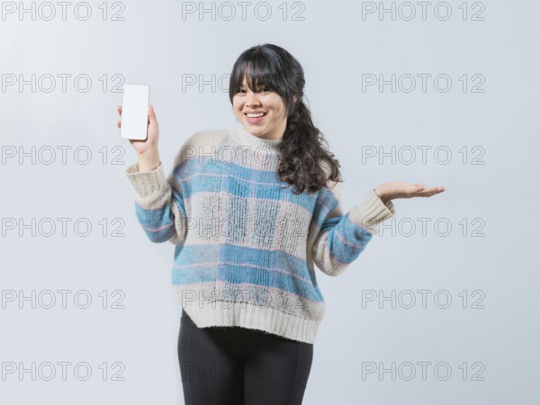 Smiling asian girl showing phone screen isolated. Beautiful asian young woman showing an