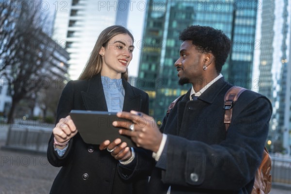 Two diverse business professionals collaborating during an outdoor meeting, sharing ideas and