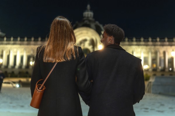 Two women holding arms, enjoying an evening stroll together while exploring the illuminated city