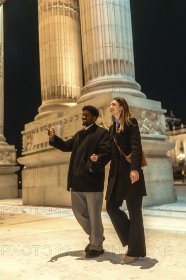 Young happy interracial couple enjoying a romantic date night, walking arm in arm and exploring the