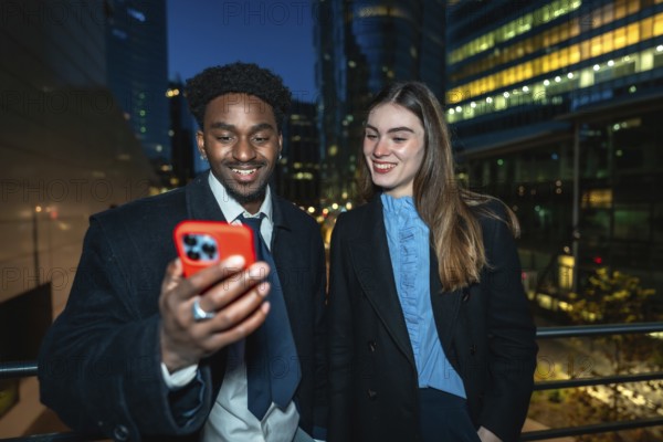 Diverse business colleagues smiling and looking at a smartphone together, enjoying a moment while