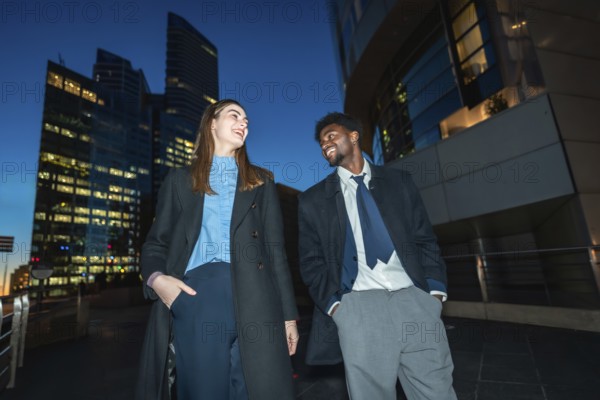 Diverse business professionals sharing a cheerful moment, smiling and talking under the city lights