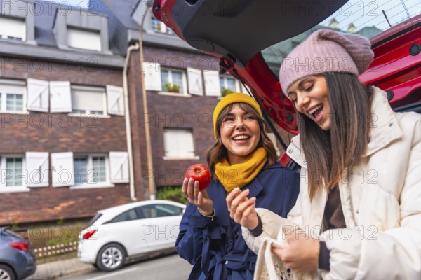 Two cheerful young multiracial women enjoying a moment of laughter while unloading fresh produce,
