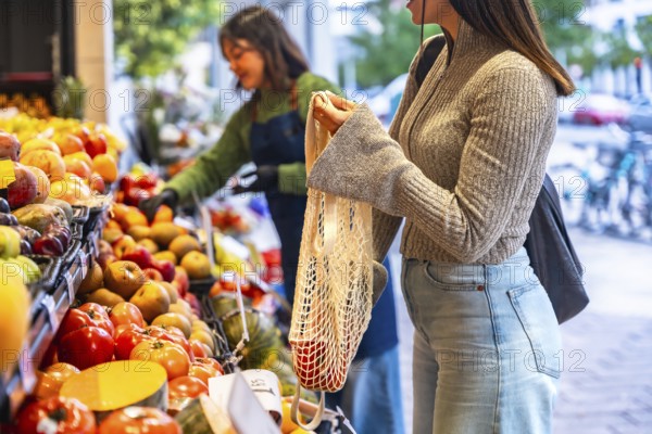 Woman holding a reusable mesh bag filled with fresh produce while shopping for organic fruits and