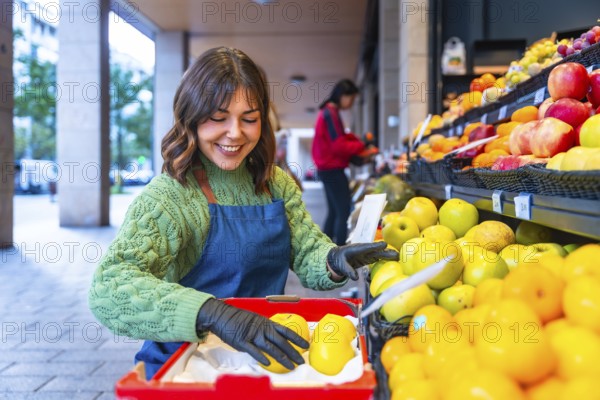 Smiling market worker in apron and gloves arranging fresh apples on a colorful outdoor fruit stall