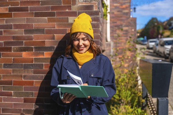 Young woman dressed in a trench coat and yellow beanie enjoying journaling and creative writing in